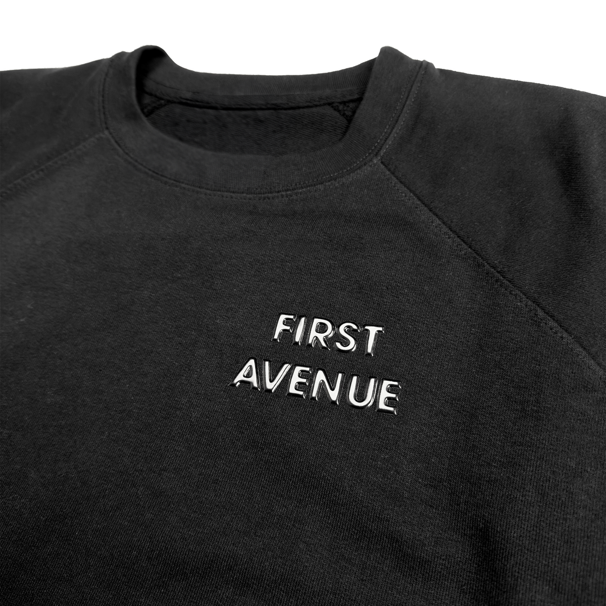 First Avenue Embossed Crewneck - a black sweatshirt with a simply styled "FIRST AVENUE" embossed on the front left pocket area.