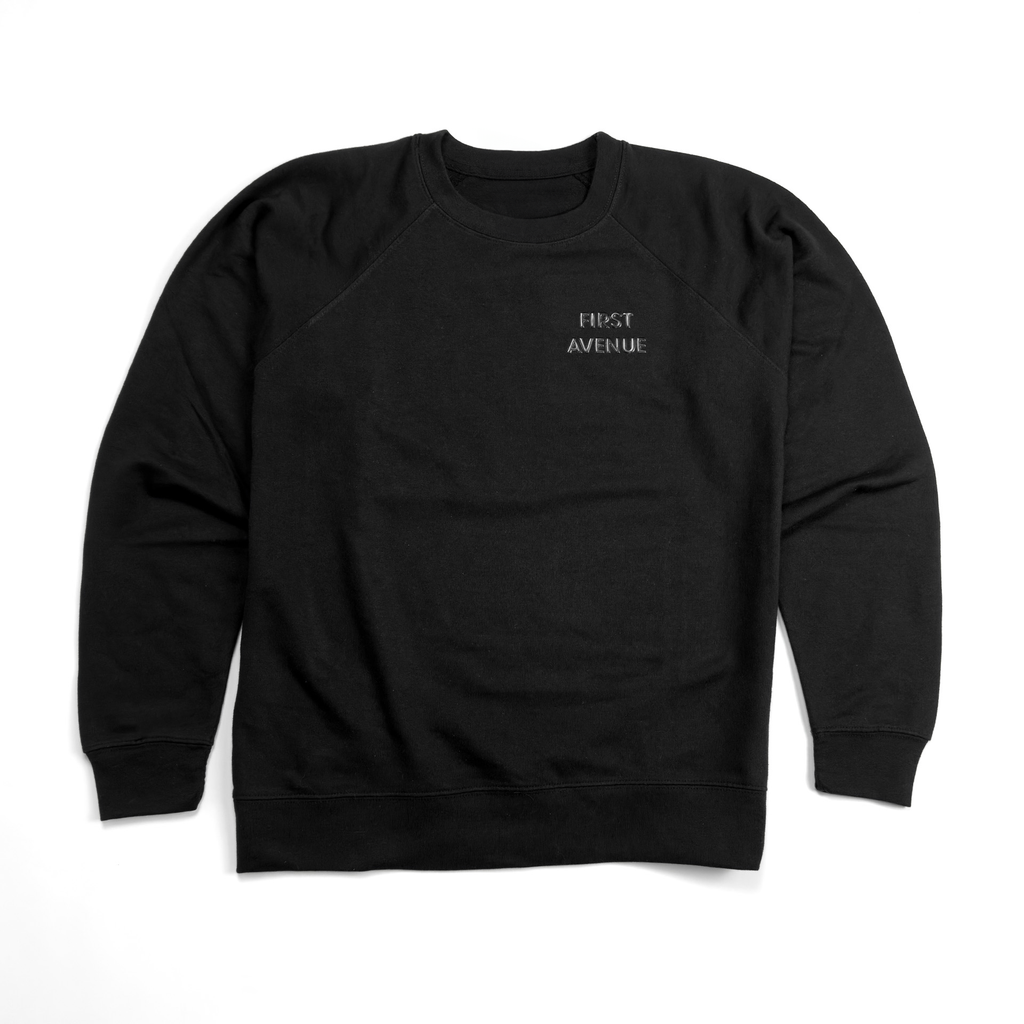 Black crewneck sweatshirt with a simply styled FIRST AVENUE embossed in black in the left pocket area.