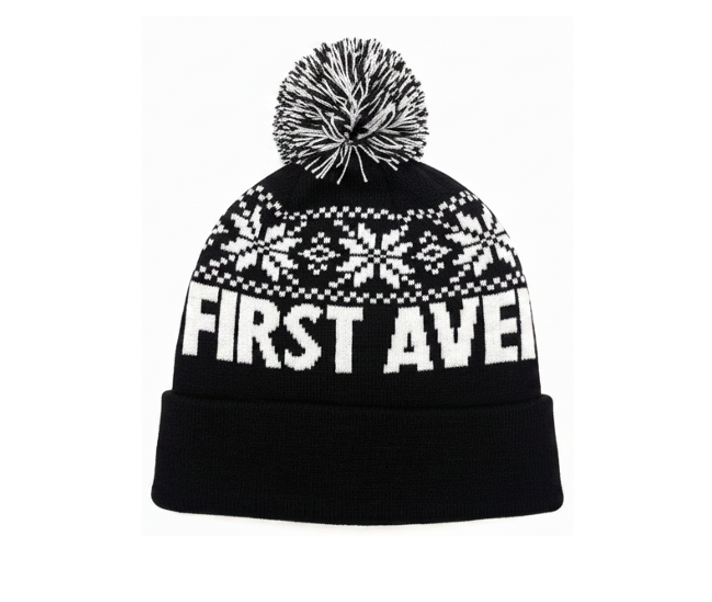 First Avenue Snowflake Pom hat - a black knit hat with white snowflakes and "FIRST AVENUE" with a black and white pom pom on the top.