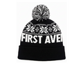 First Avenue Snowflake Pom hat - a black knit hat with white snowflakes and "FIRST AVENUE" with a black and white pom pom on the top.