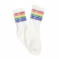 A pair of white crew socks with 'FIRST AVENUE' printed repeatedly in a rainbow color sequence on the cuff.