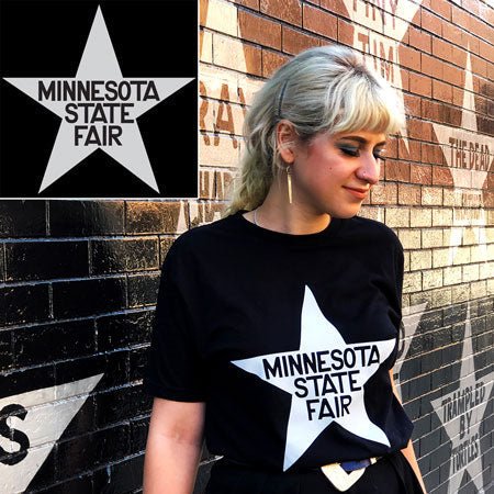 Person wearing a black t-shirt with a white star and 'Minnesota State Fair' text