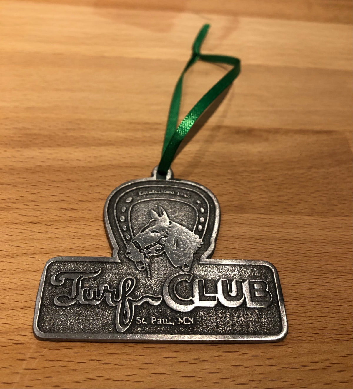Metal 'Turf Club' ornament featuring the Turf Club logo.
