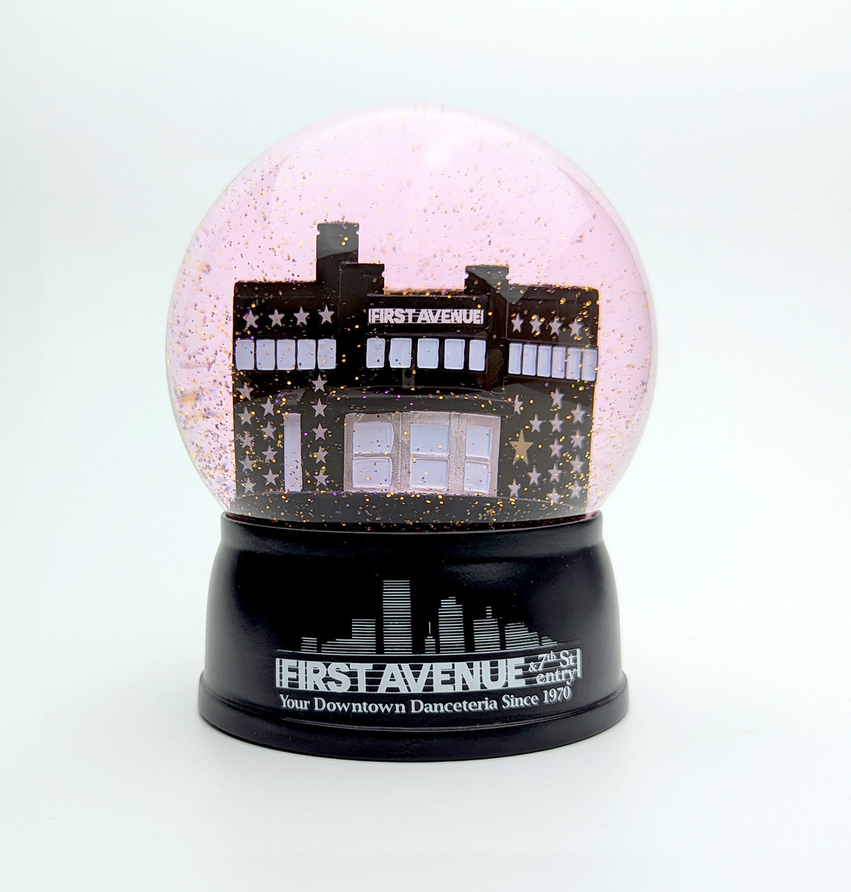 Snow globe with mini First Avenue building inside. Purple glitter "snow." The First Avenue logo in white on a black base.