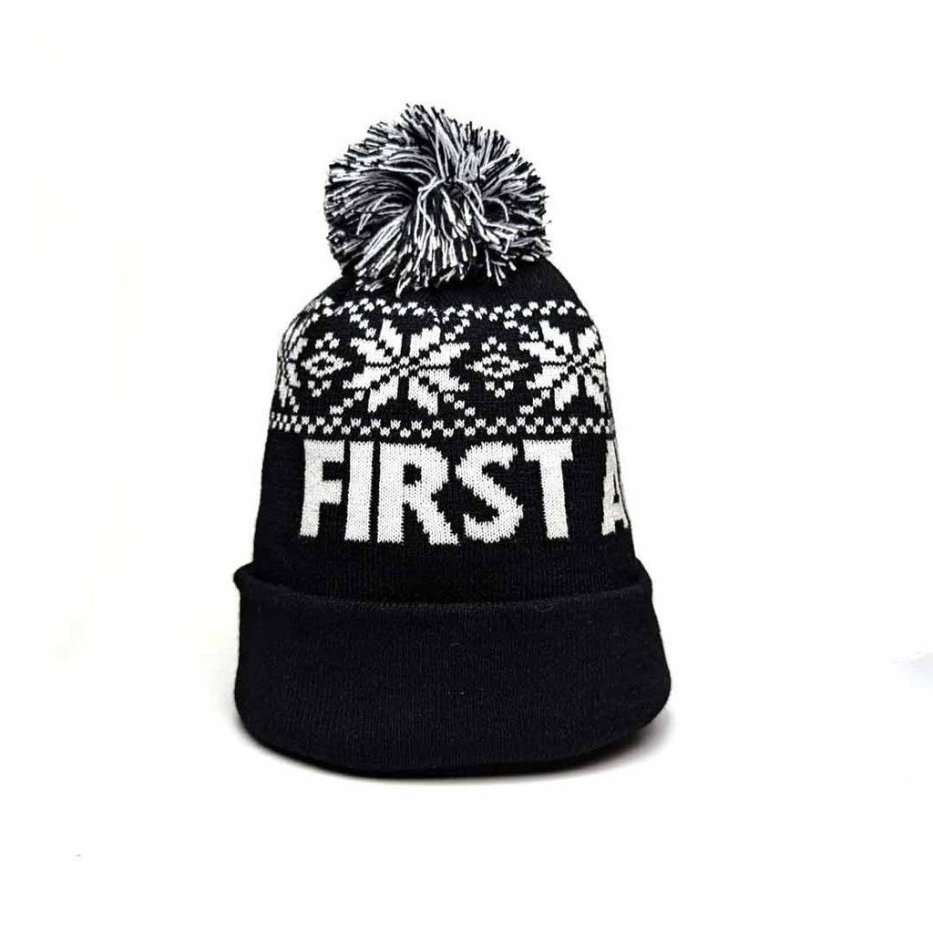 Black knit winter hat with white snowflake pattern and 'First Avenue' in white. Has a black and white pom pom on top.