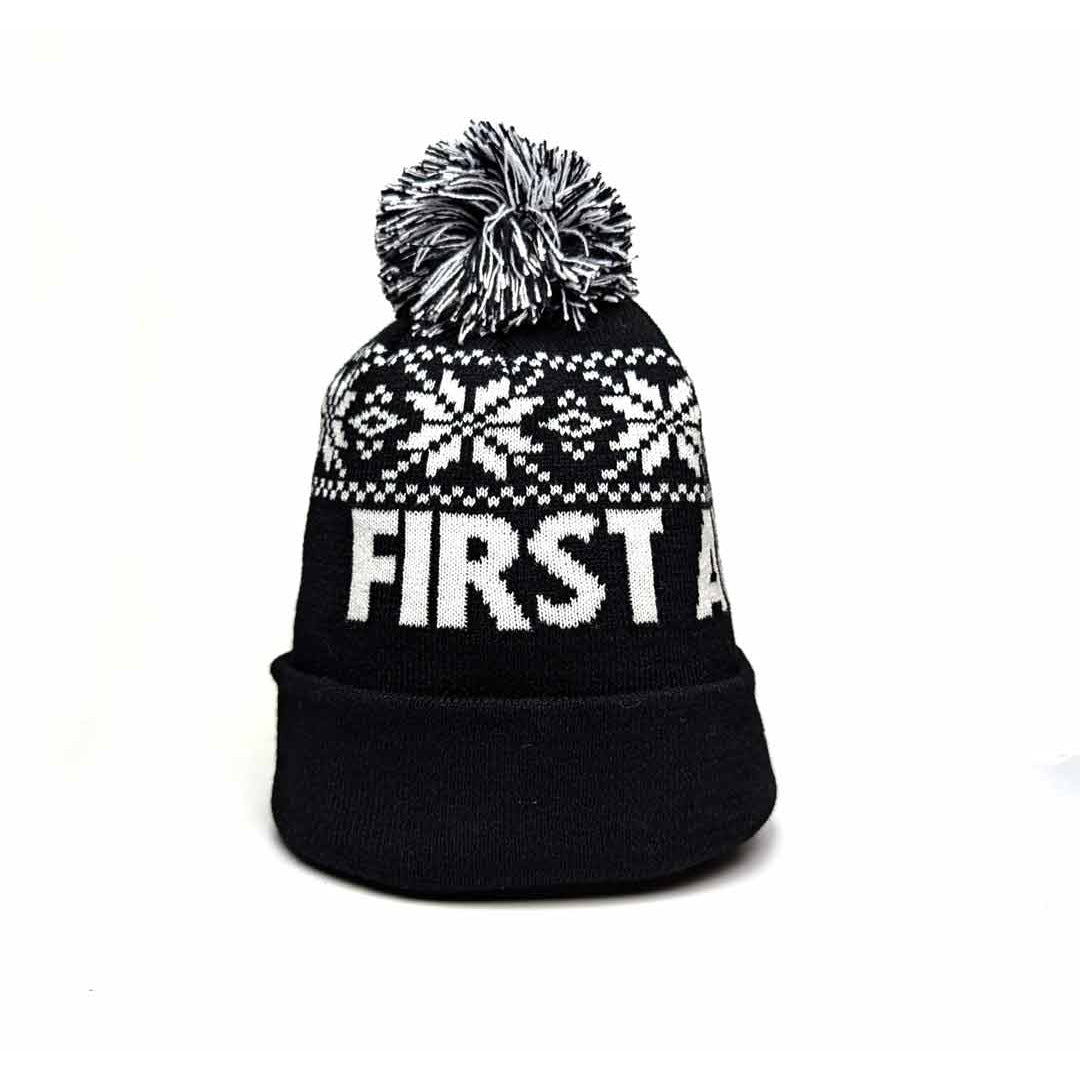 Black knit winter hat with white snowflake pattern and 'First Avenue' in white. Has a black and white pom pom on top.
