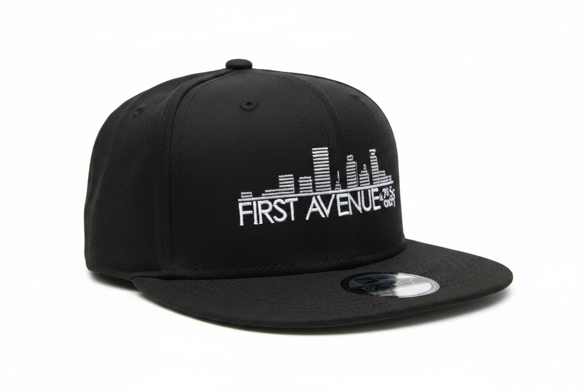 First Avenue Flatbill in black with the First Avenue logo embroidered in white on the front.